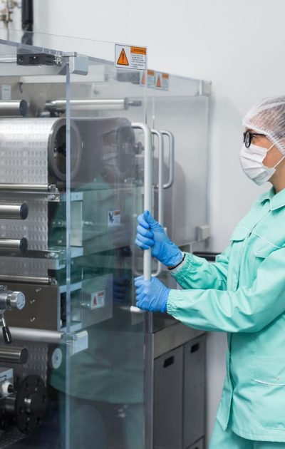 caucasian factory worker in blue lab suit work with machine, machine with glass panels